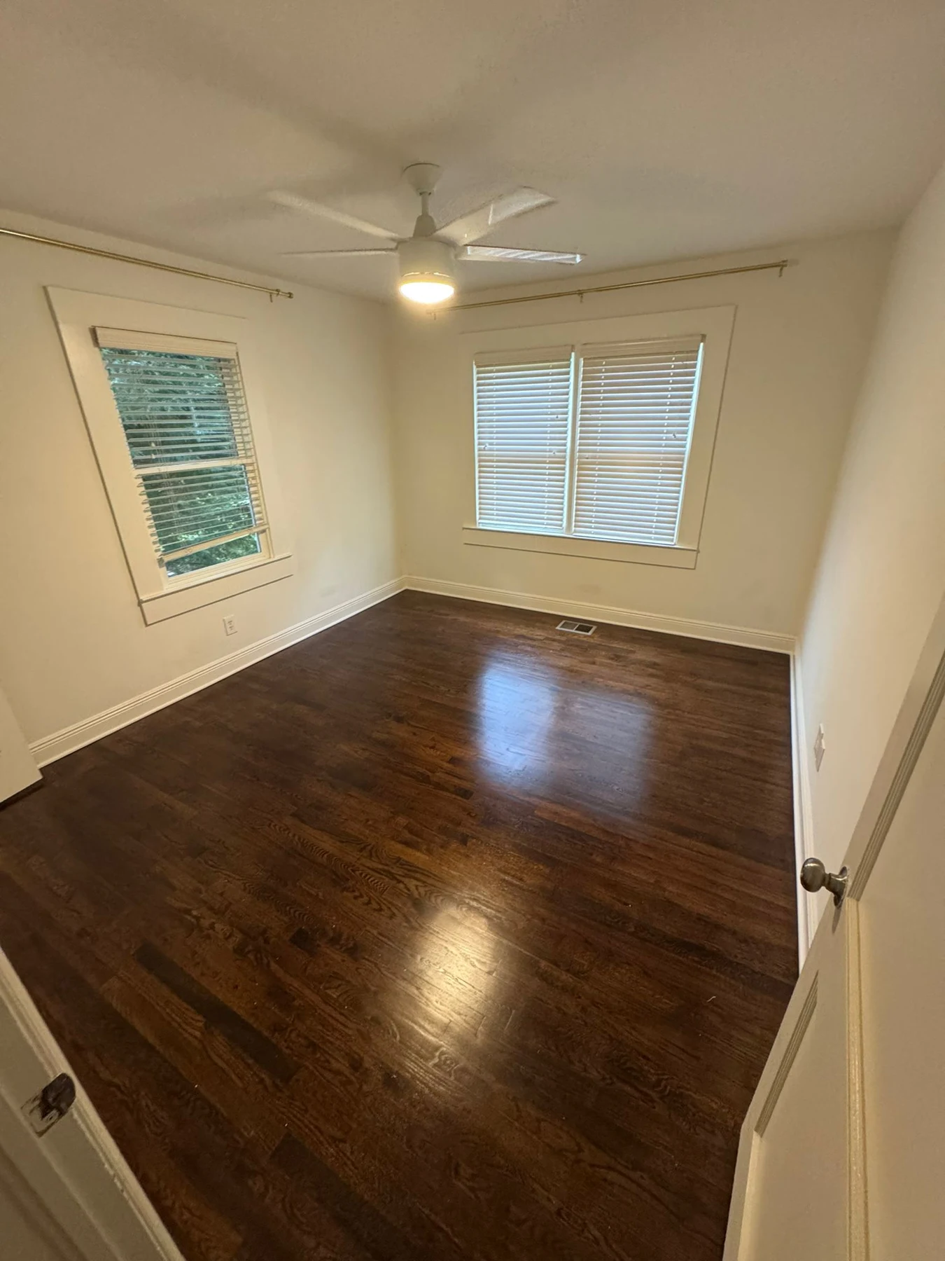 Bright empty room with wood floor and two windows